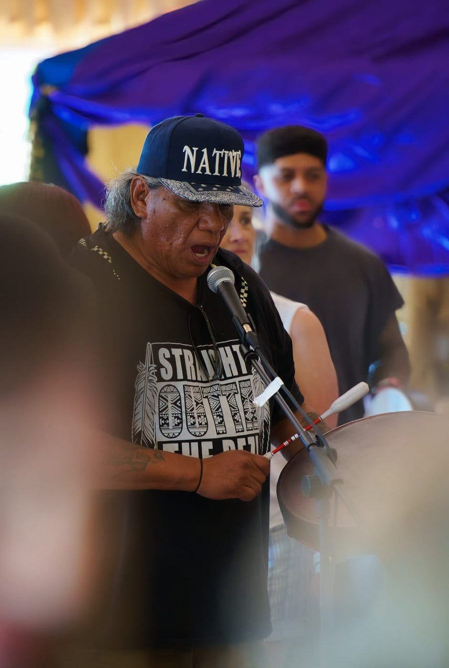 Singing into the mic over the steel drum